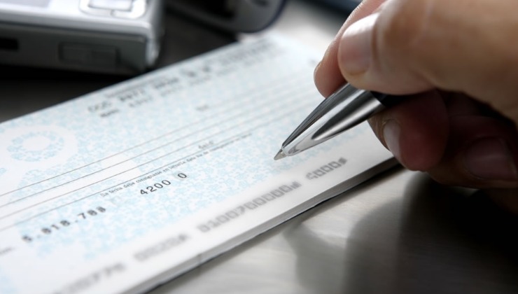 Firma su un assegno soldi (foto debitobancario) - mediaoneonline.it